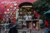 An outside wine bar set against a red wall decorated by dozens of kitchy clocks