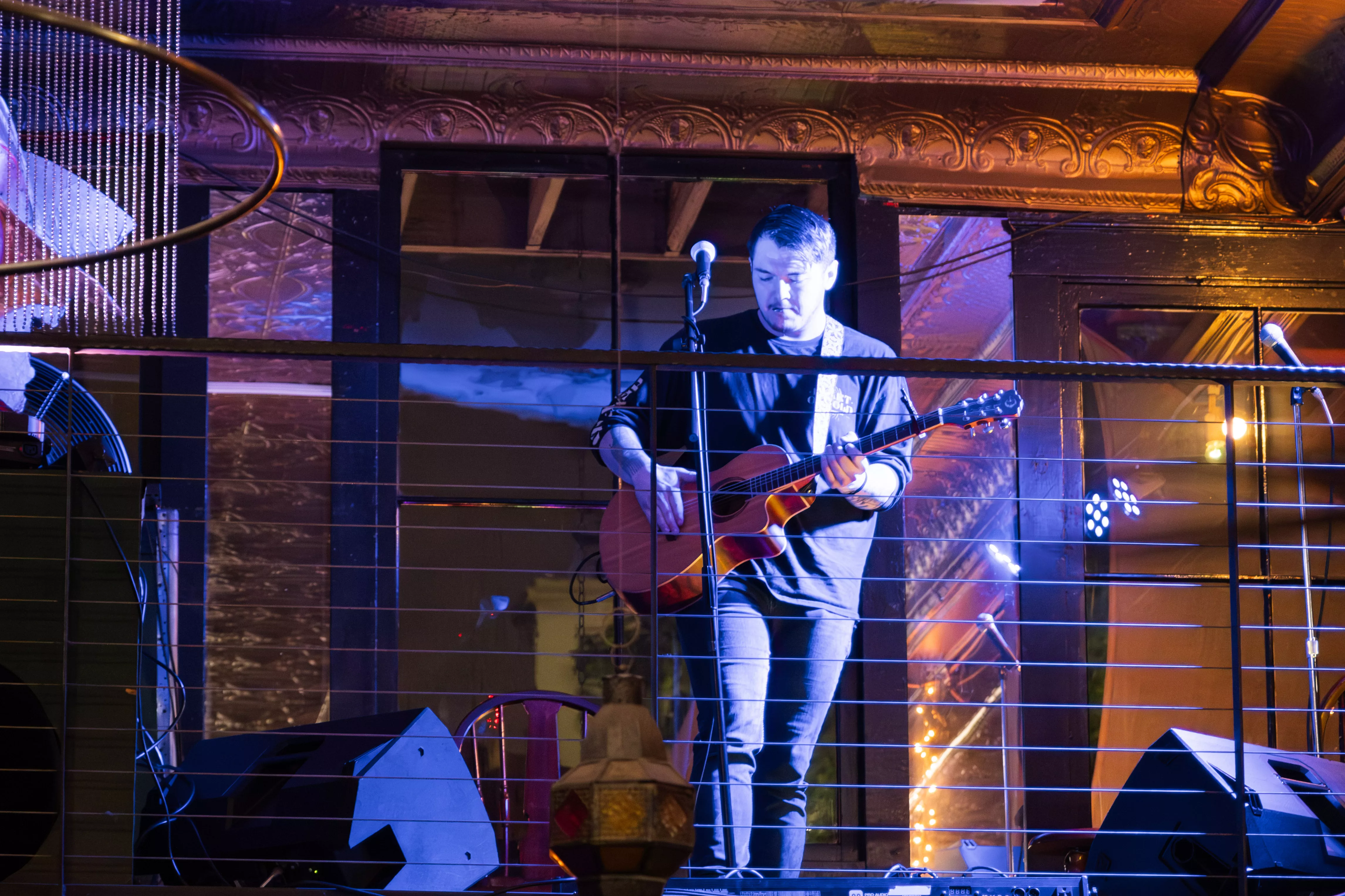 person playing guitar standing on the balcony of Back to the Grind