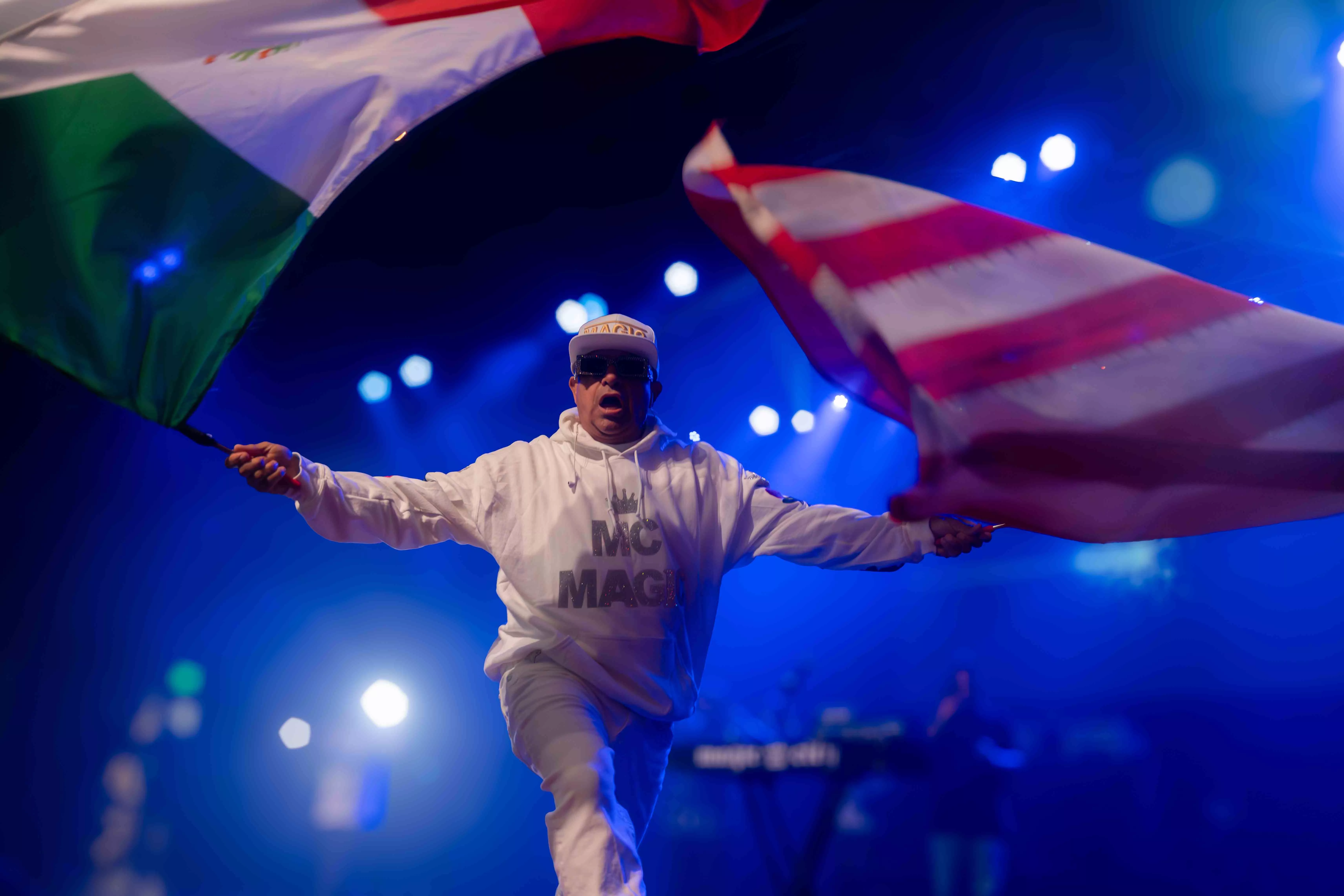 MC Magic waves a Mexican and a US flag as he walks out to the stage during his performance at the RMA