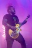 A male presenting musician plays guitar on the stage at the Riverside Municipal Auditorium