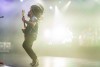 A male presenting musician plays guitar on the stage at the Riverside Municipal Auditorium