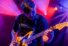 A male presenting musician plays guitar on the stage at the Riverside Municipal Auditorium