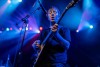 A male presenting musician plays guitar on the stage at the Riverside Municipal Auditorium