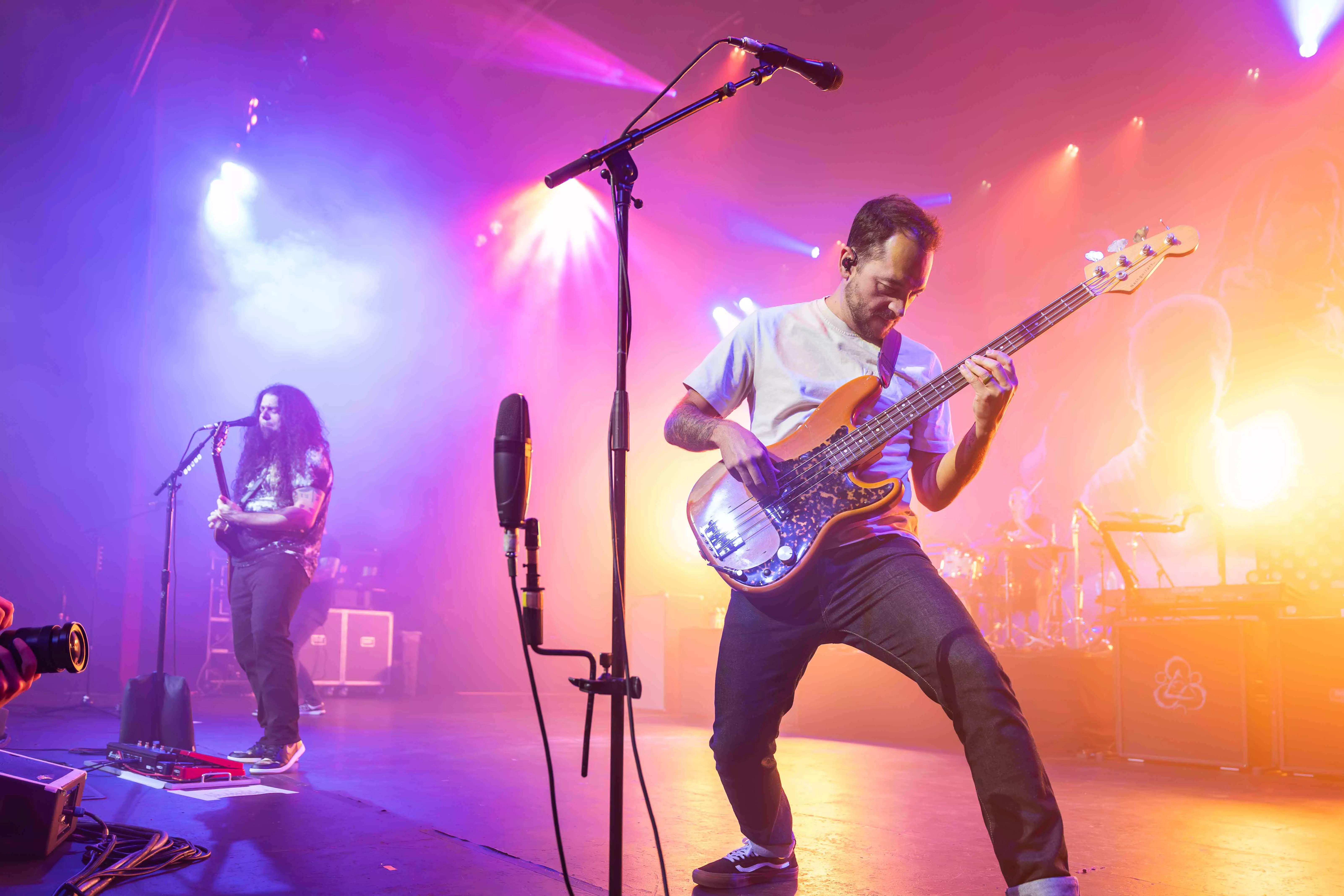 Two male presenting musicians play guitar on the stage at the Riverside Municipal Auditorium