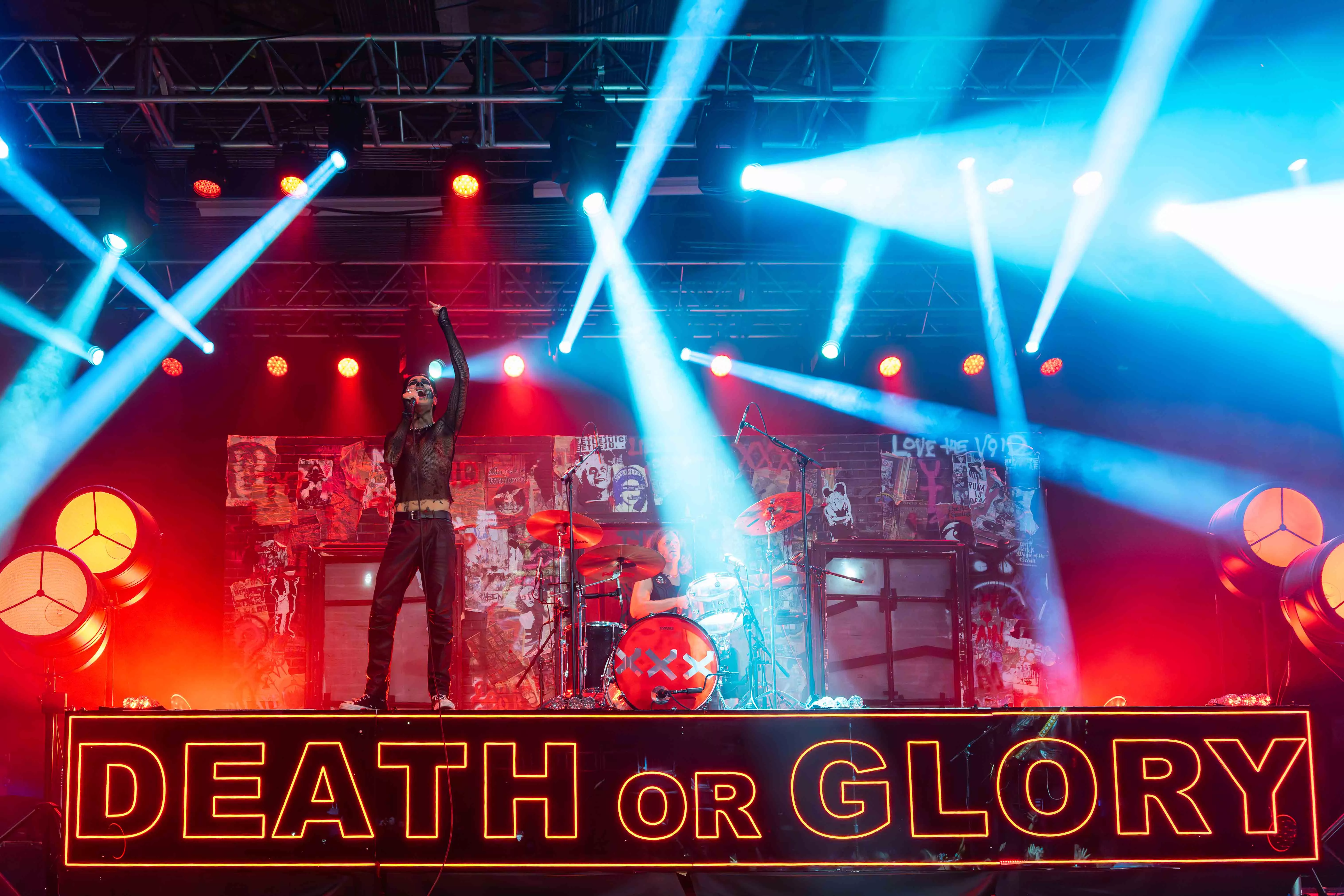 A band performs on stage with a large sign that says Death or Glory at the house of blues in anaheim