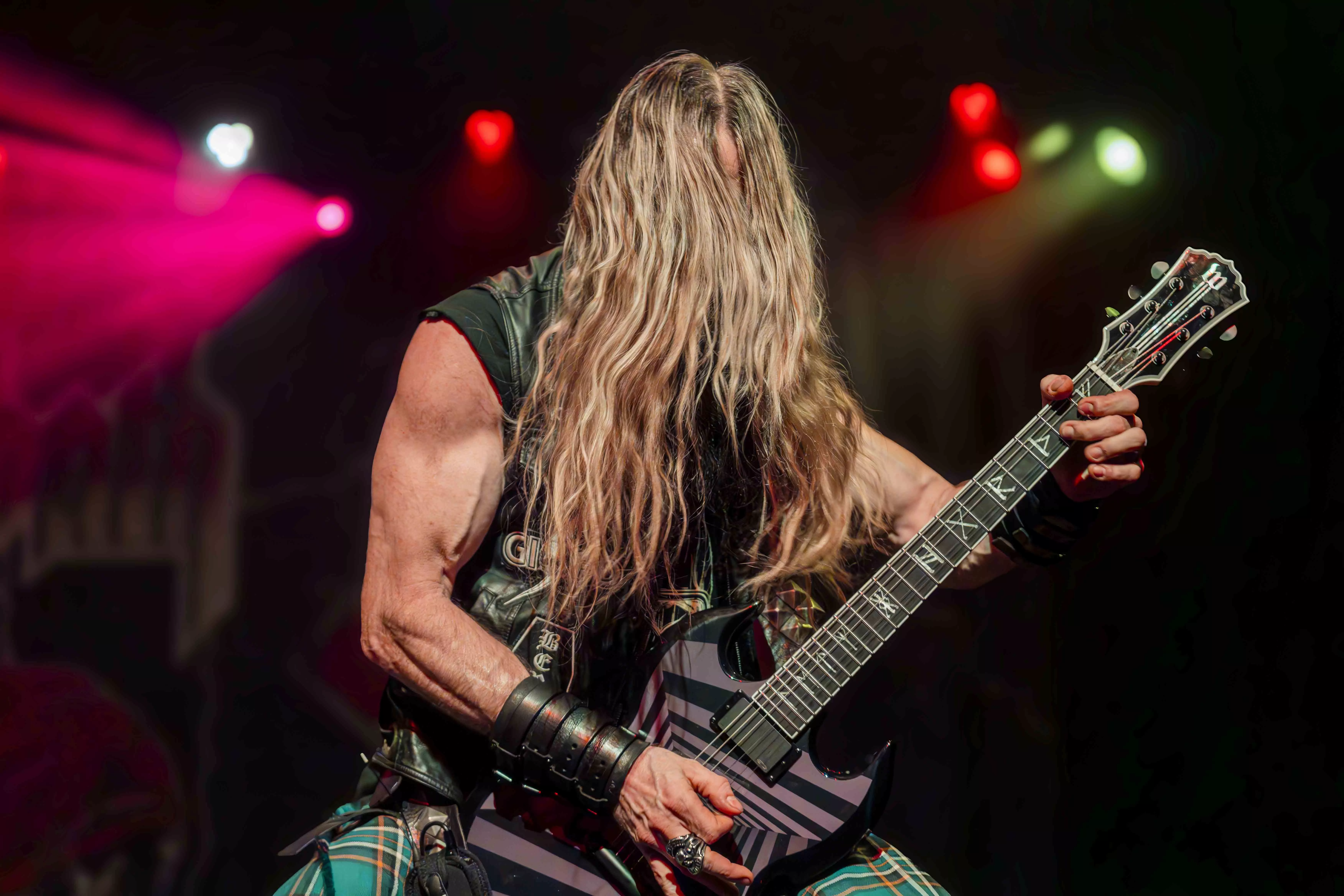 A male presenting musician plays guitar on the stage at the Riverside Municipal Auditorium