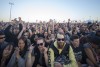 A crowd of people with raised hands cheer for the band