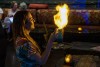 A server ignites a tiki drink using overproofed alcohol sprayed through a flame