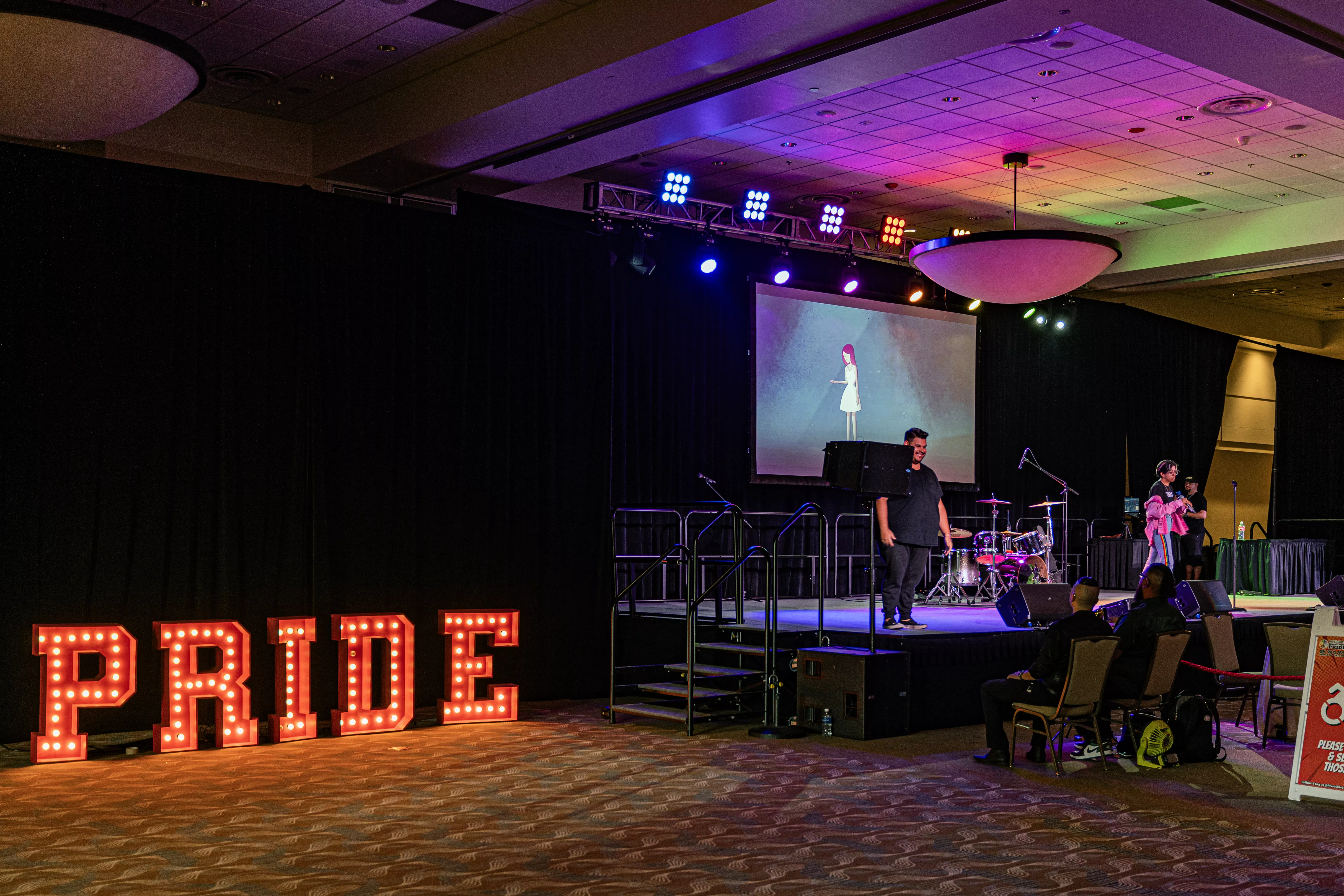 Pride in Red lights next to a stage