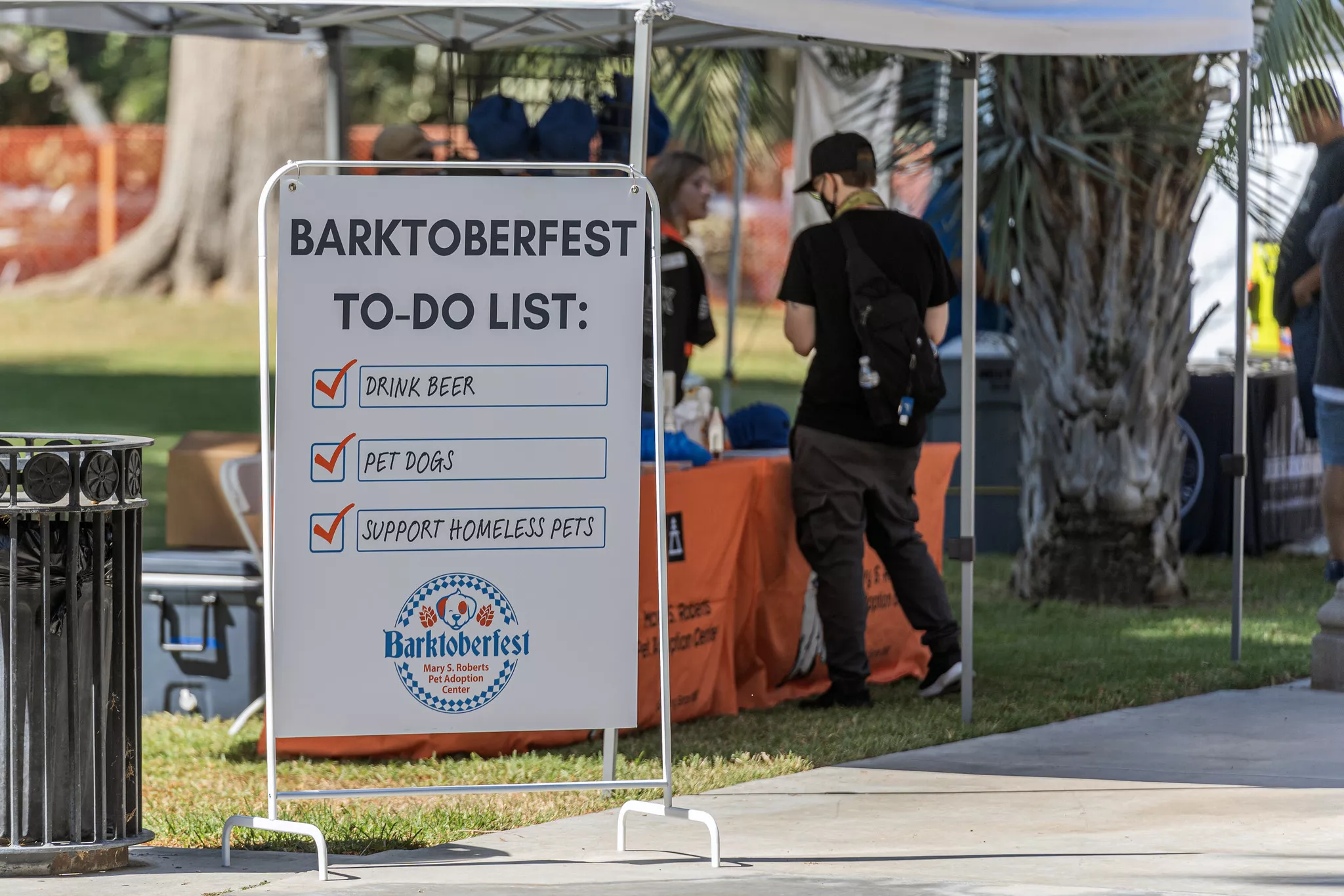 The sign at the front entrance of Barktoberfest reminds event goers to drink beer pet dogs and support homeless pets during the inaugural festival held at White Park in Riverside CA on Oct 14