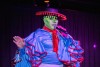 A drag queen dressed like an alien speaks on stage