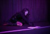 A drag queen lays on stage with an open book