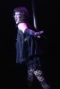 A drag queen performs on stage against a dancing pole