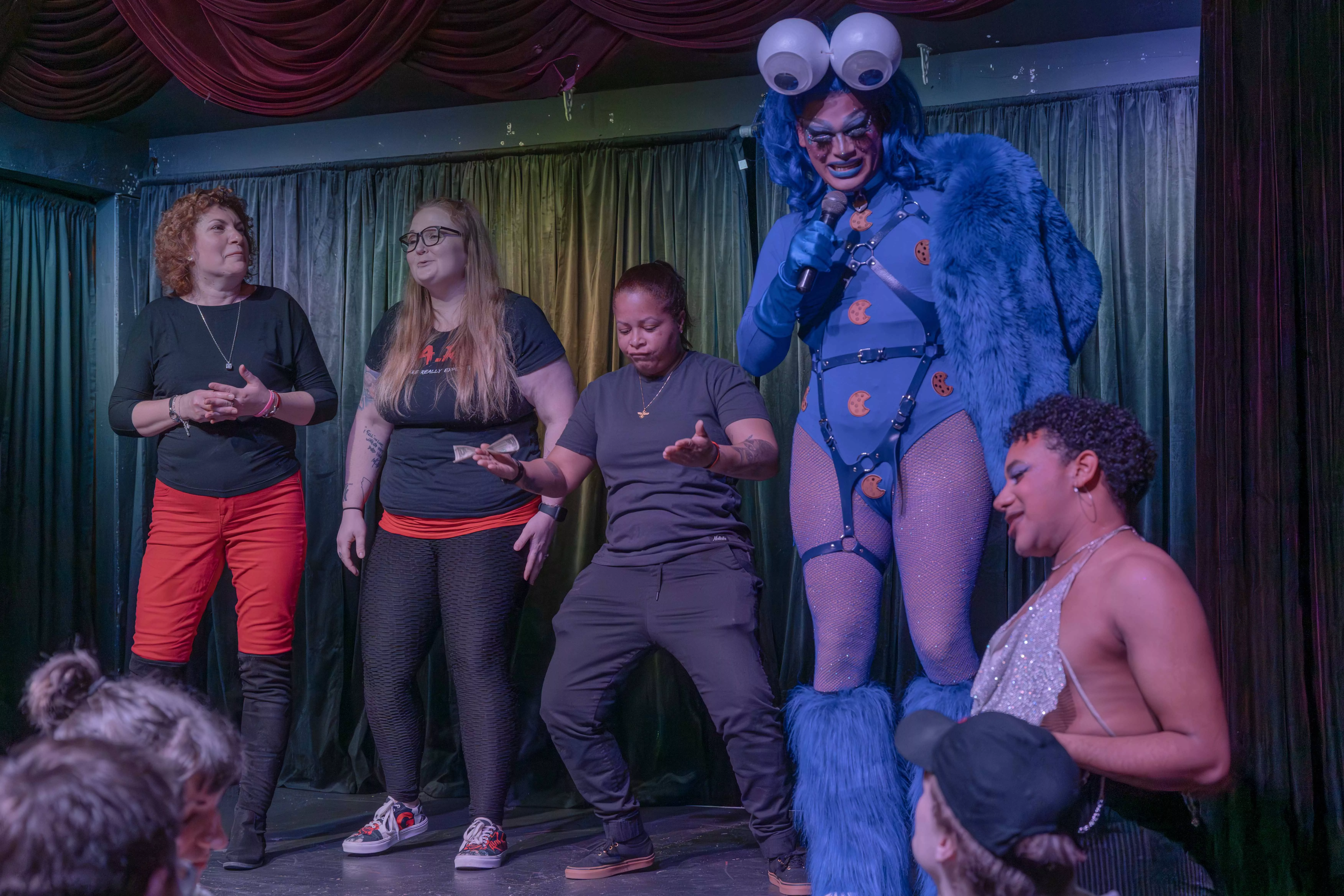 Attendees of a drag show on stage with the drag queen