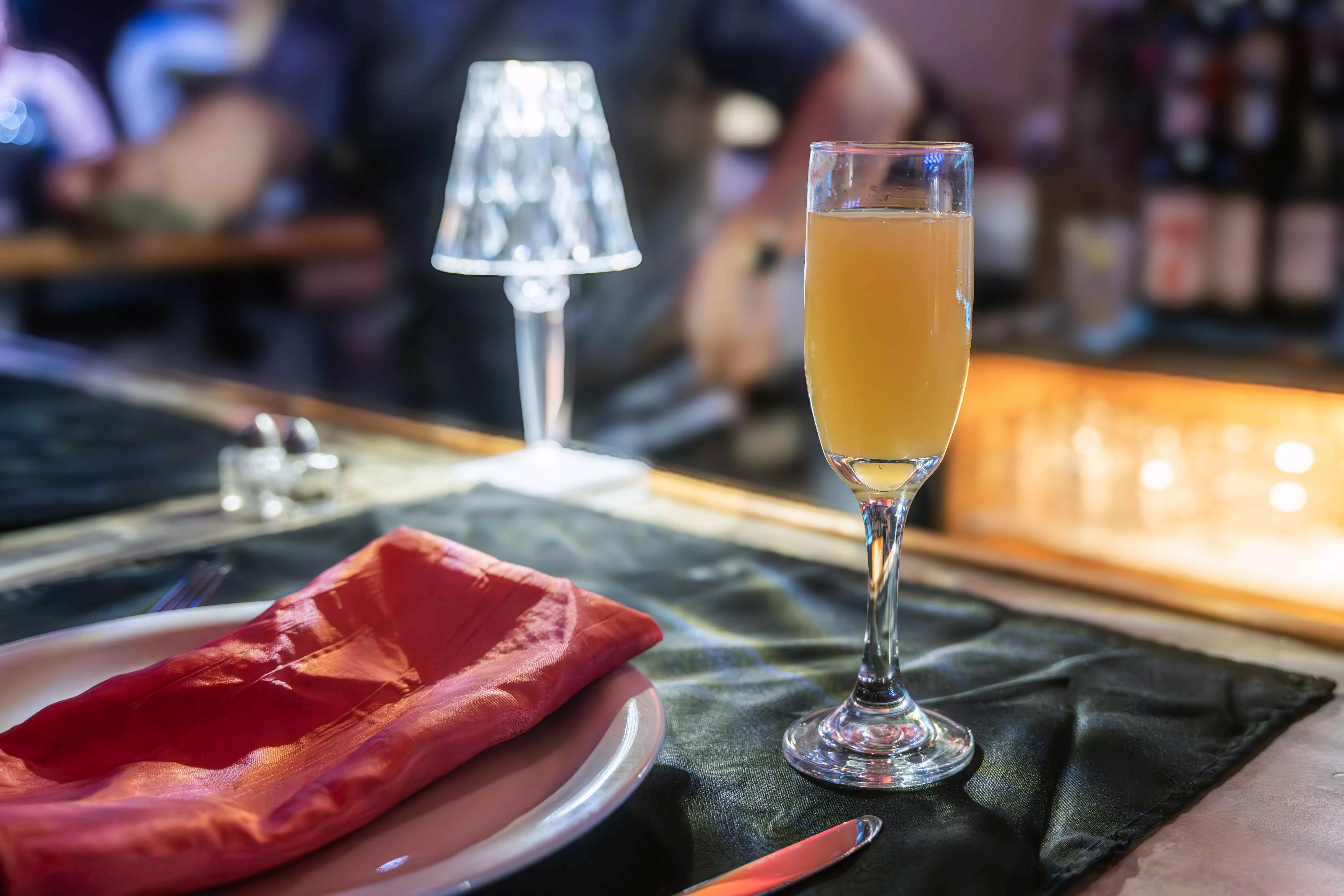 A champange flute of orange juice sitting on a bar