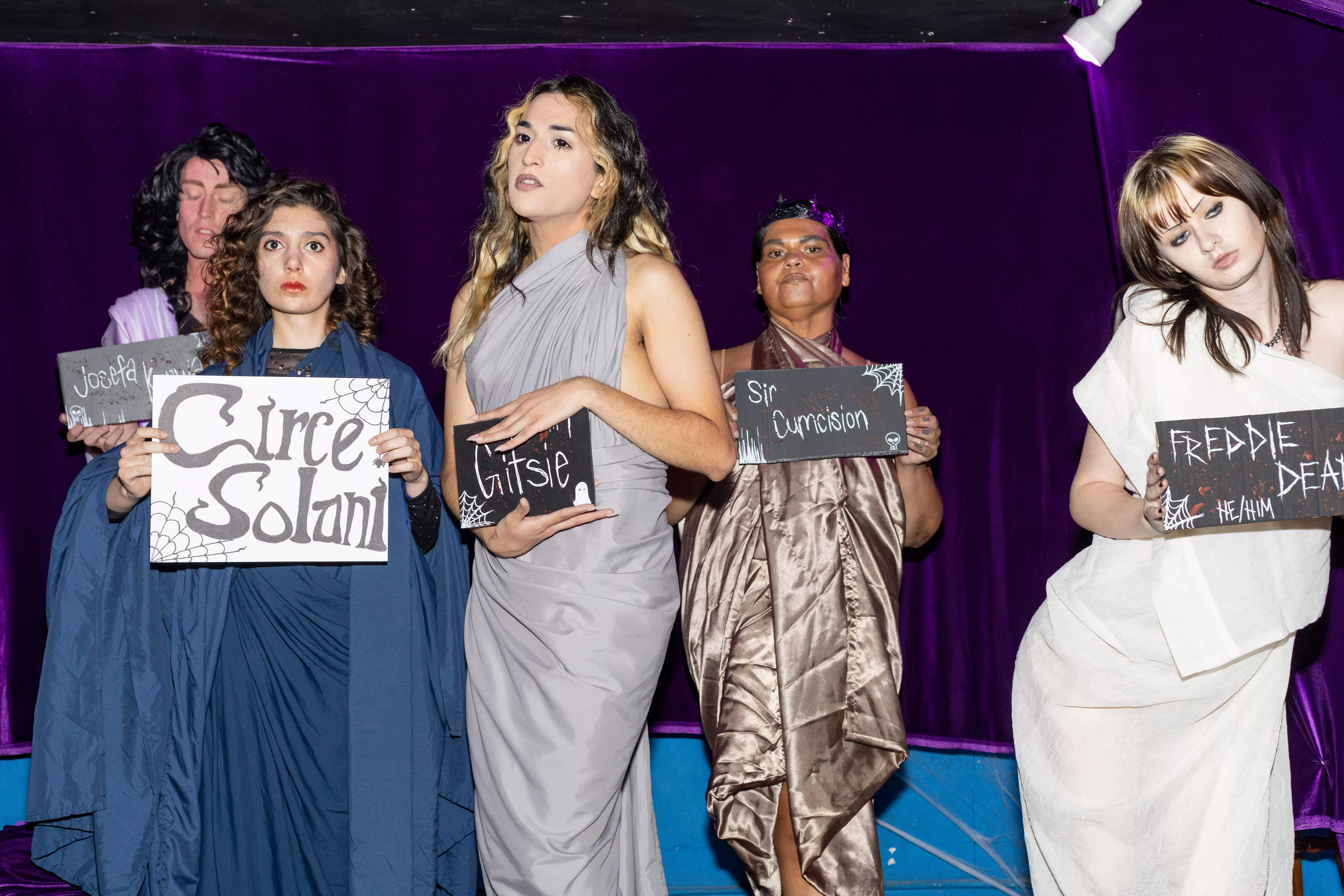 Live art performers hold signs on stage