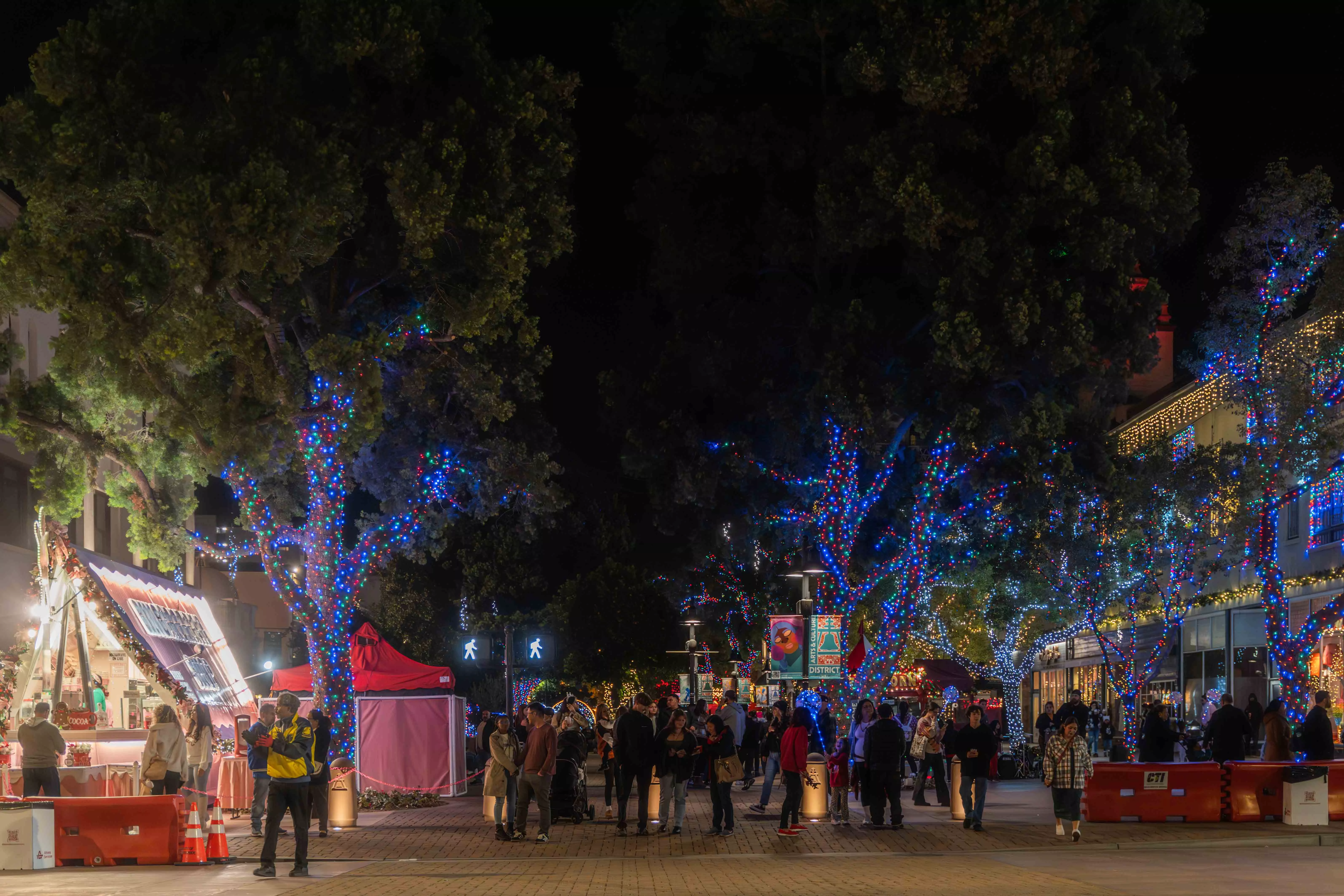 People walk along a promenade decorated for Christmas