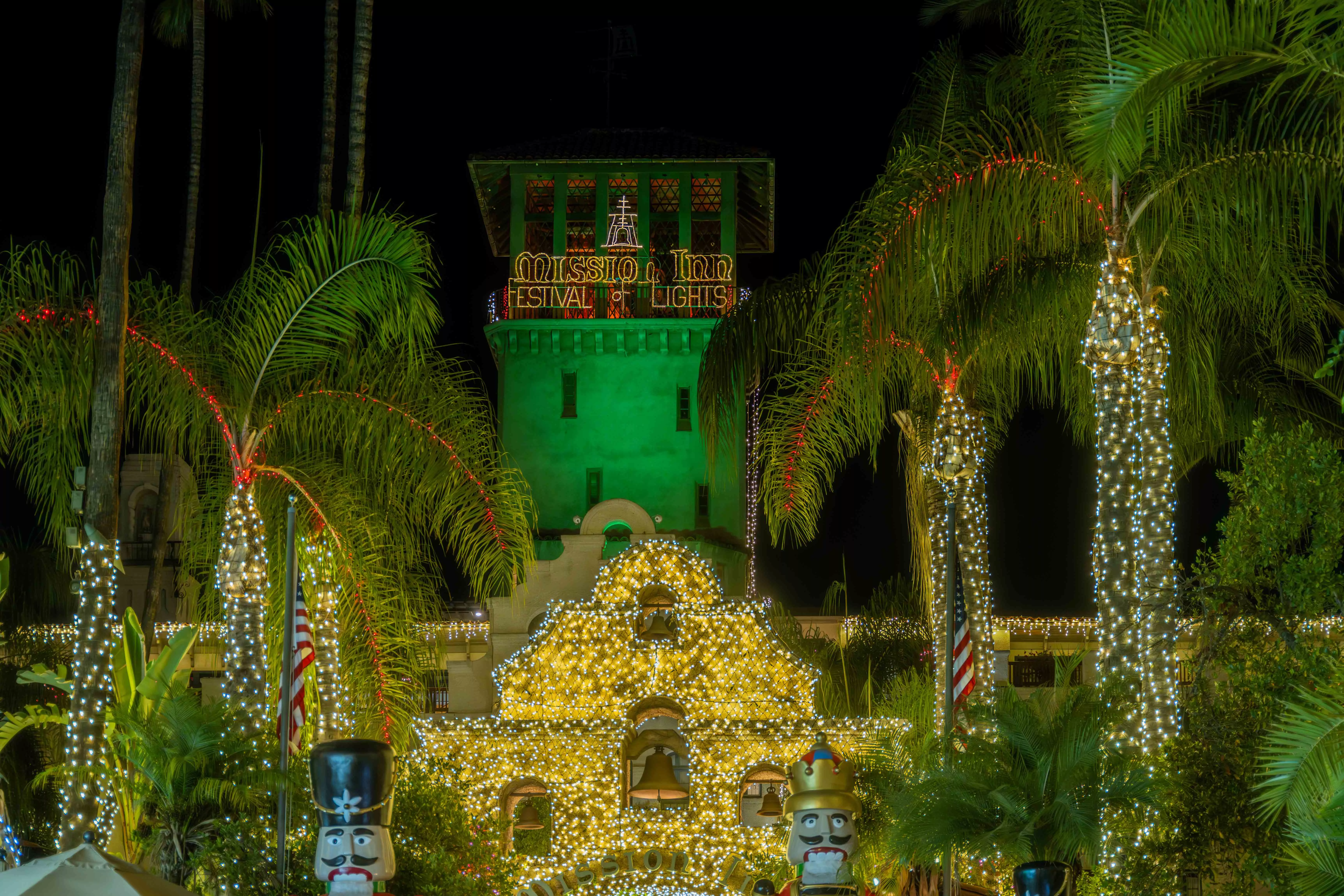 A hotel entryway is decorated with thousands of christmas lights with some spelling out Mission Inn Festival of Lights