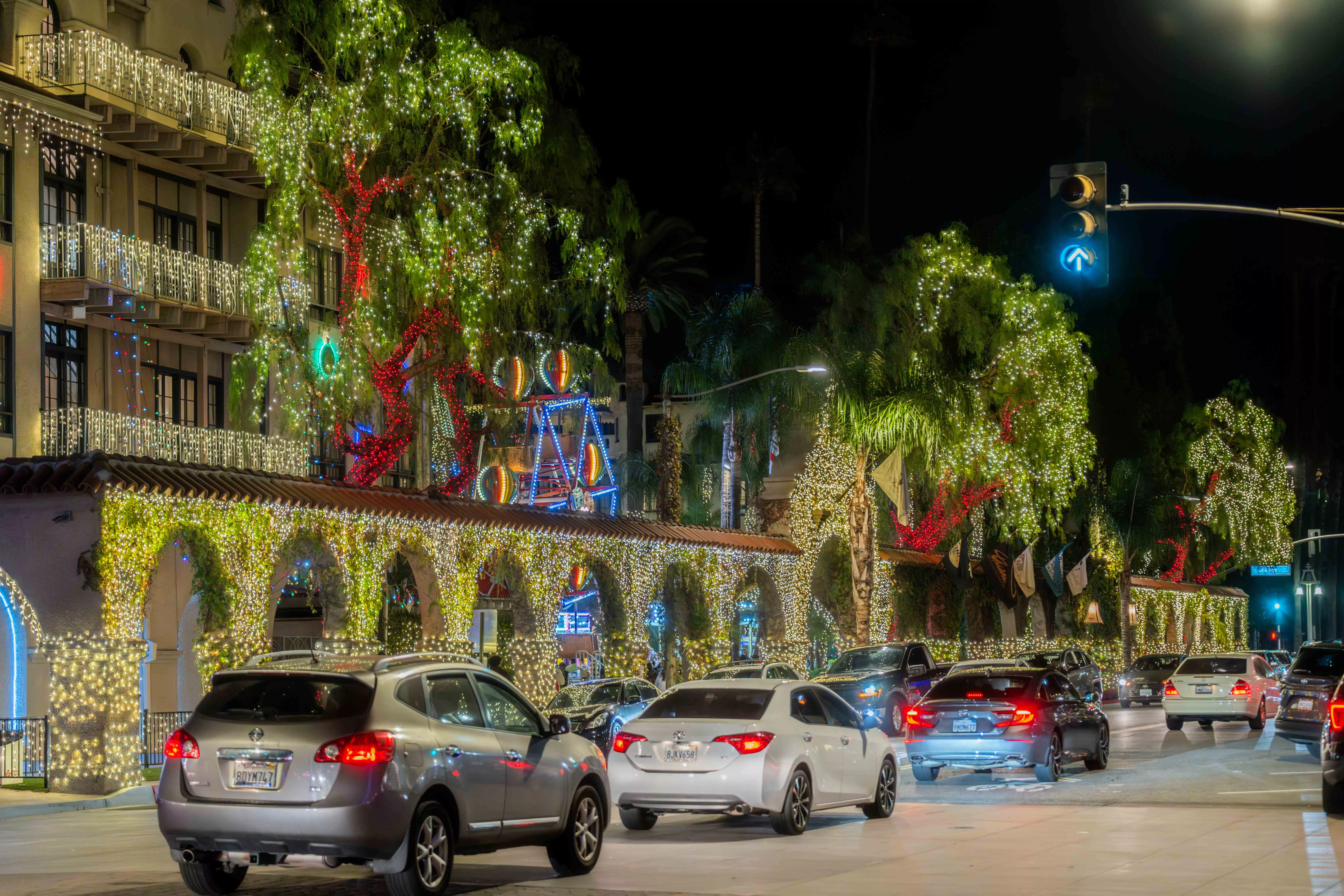 cars on drive down a street past a hotel completely covered in christmas lights