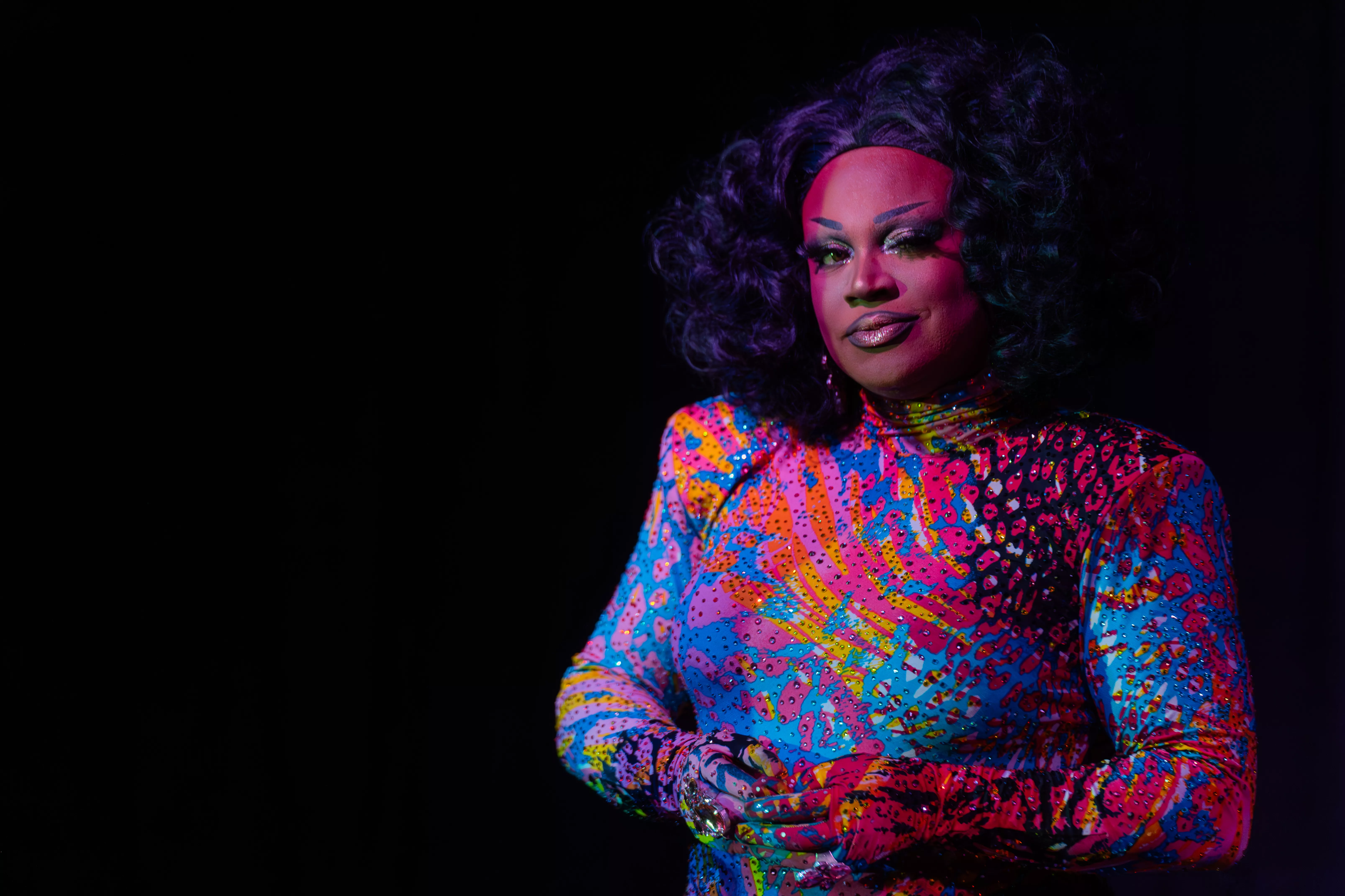 A female presenting performer against a black back drop