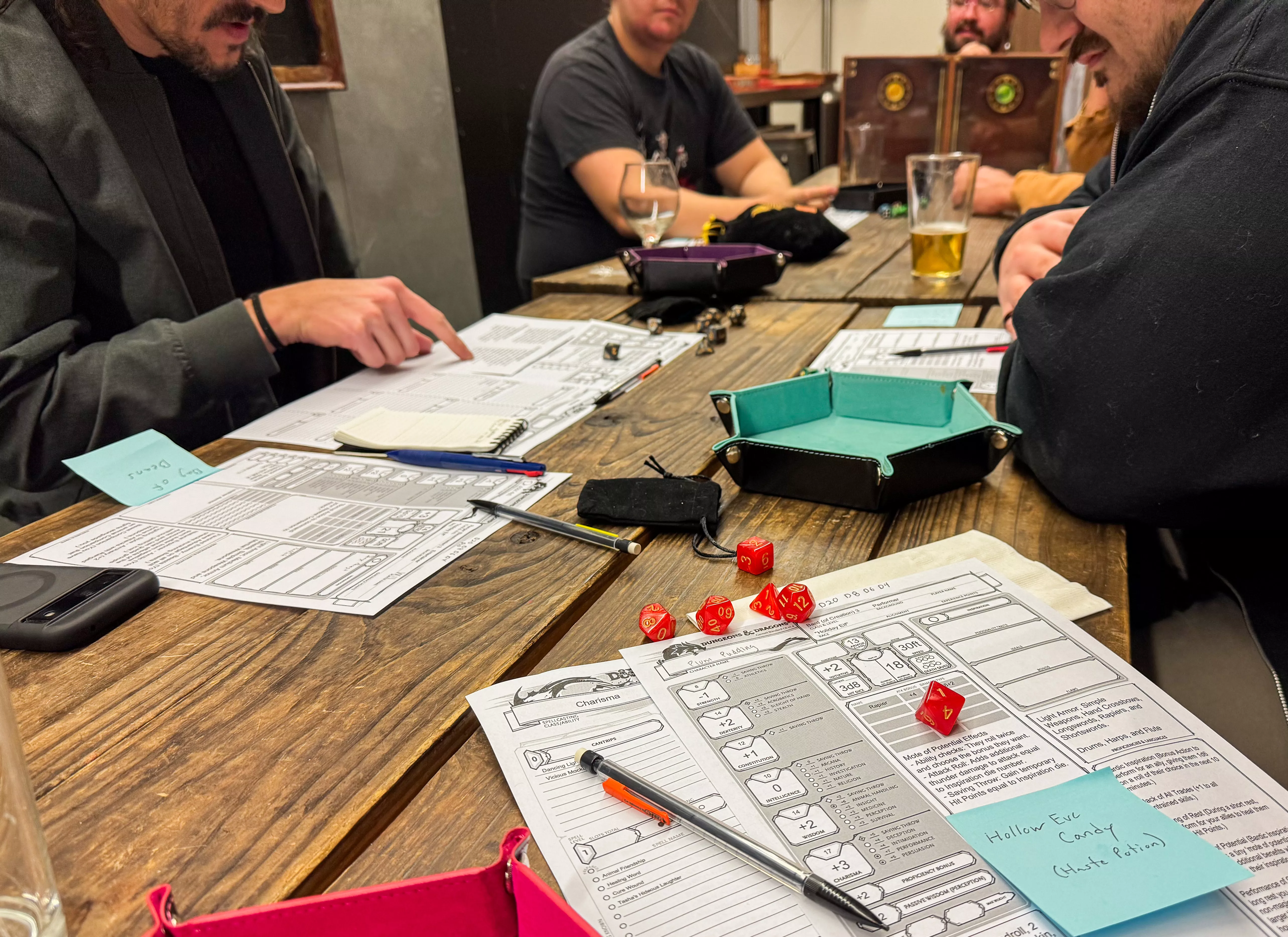 character sheets and dice on the table with people playing Dungeons and Dragons