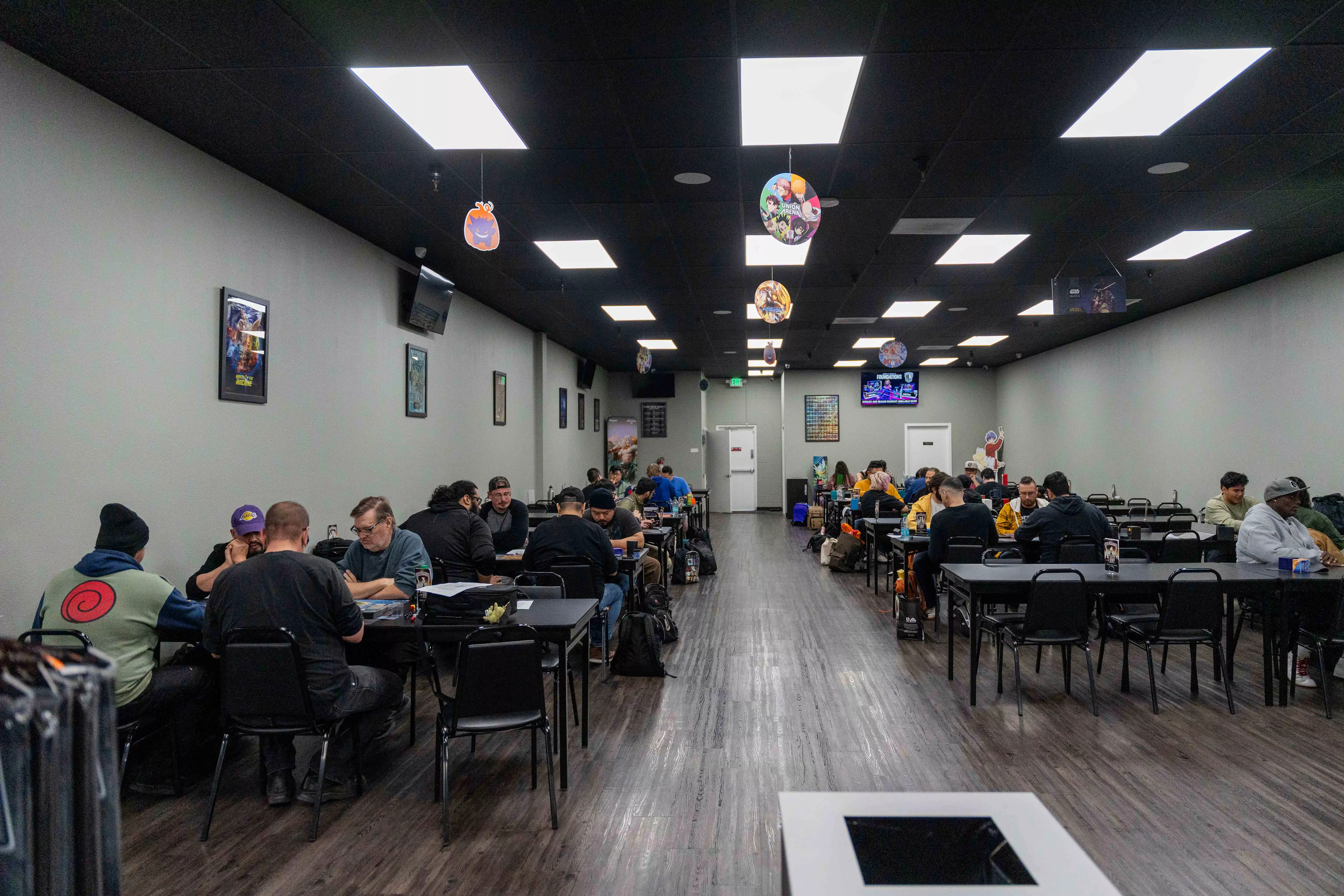 People sit at gaming tables playing various table top games at Top Deck Keeps gaming area in Riverside Ca on Nov 24