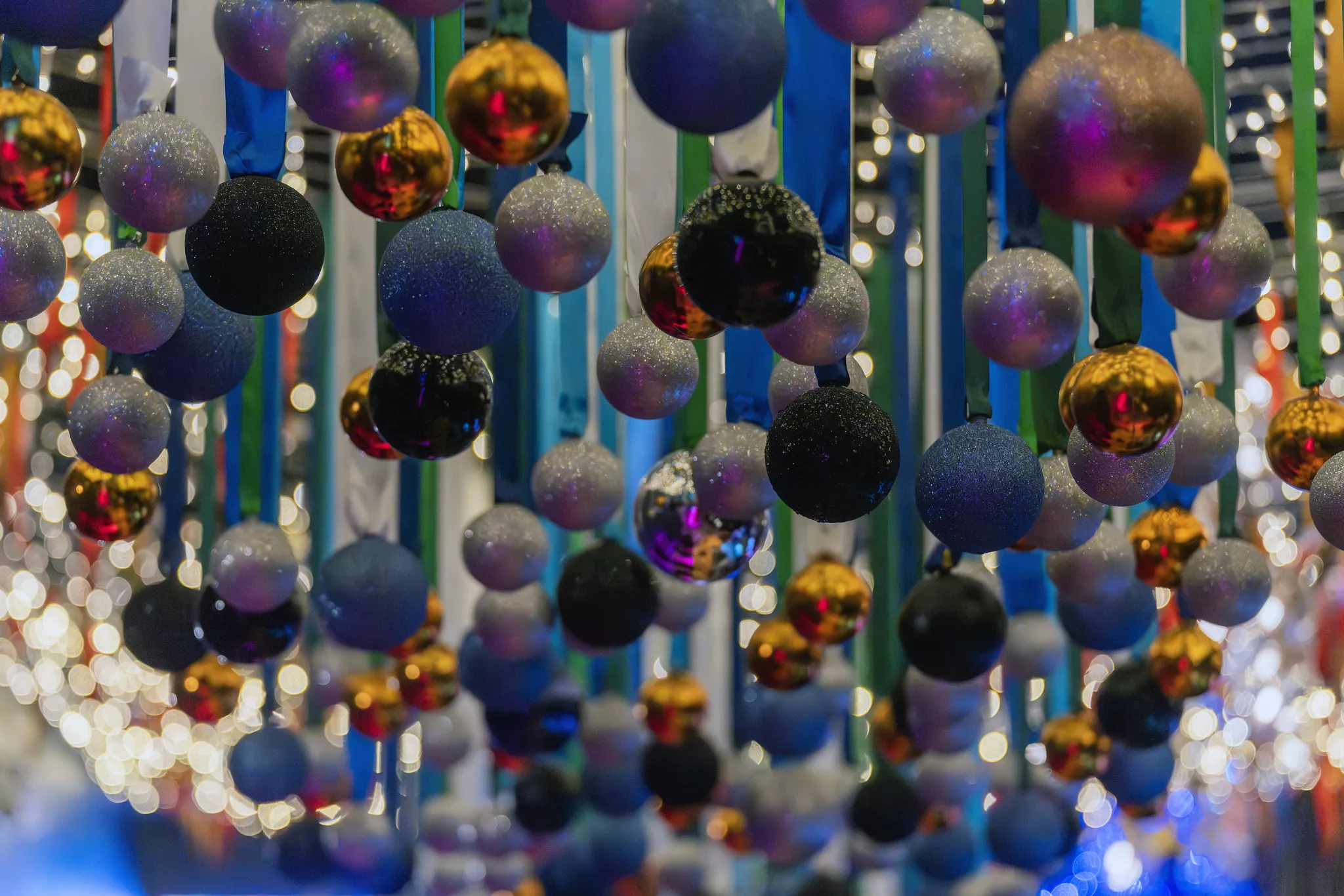 Christmas Ball shaped ornaments hang from a ceiling in a cluster