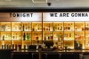 A wall of liquor bottles back lit with a marquee above that says Tonight We Are Gonna