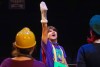 Performer reaches into the sky with a sock puppet on hand during a play production