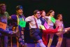 Performers dance on stage to a musical number during a play production