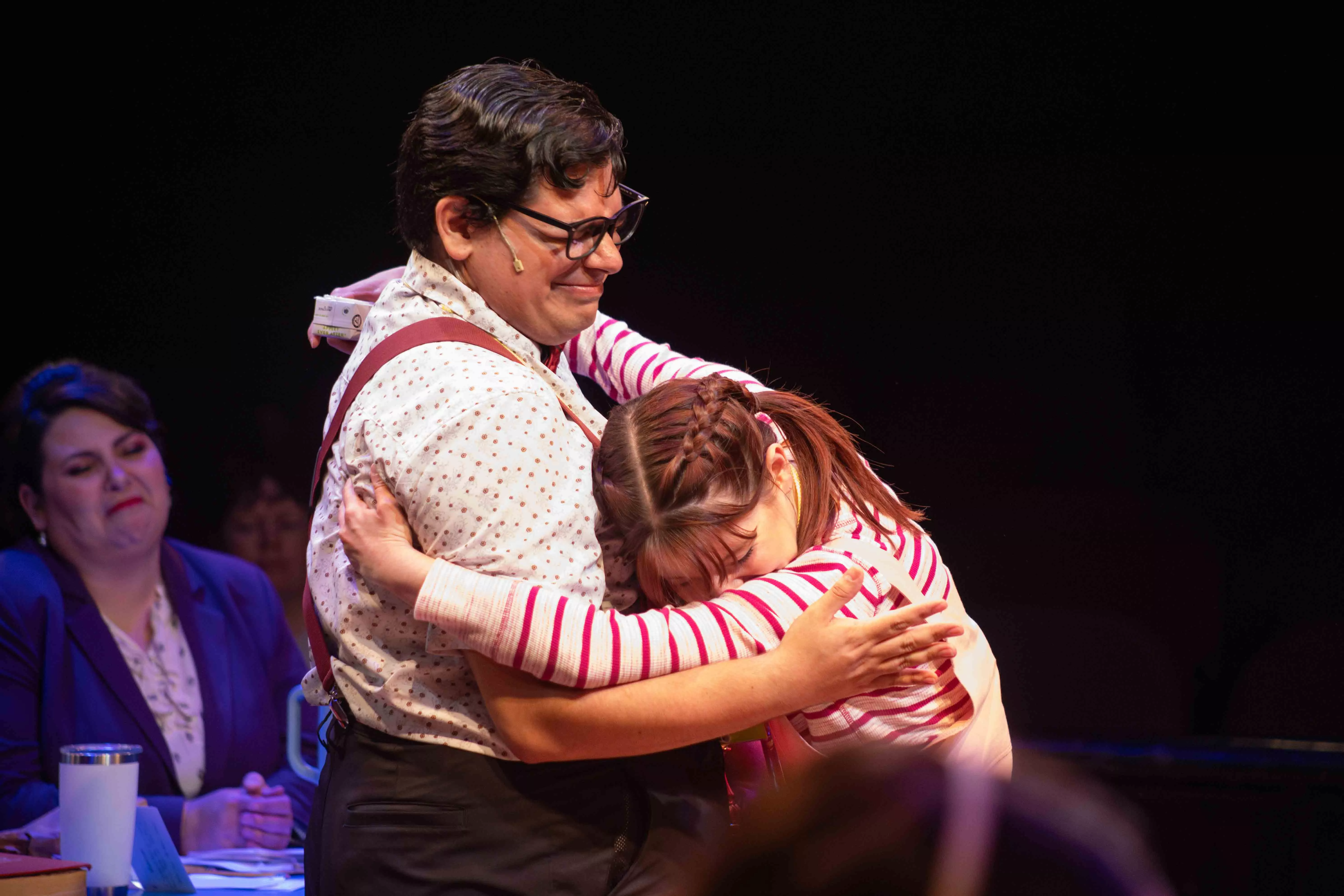 Performers embrace each other on stage during a play