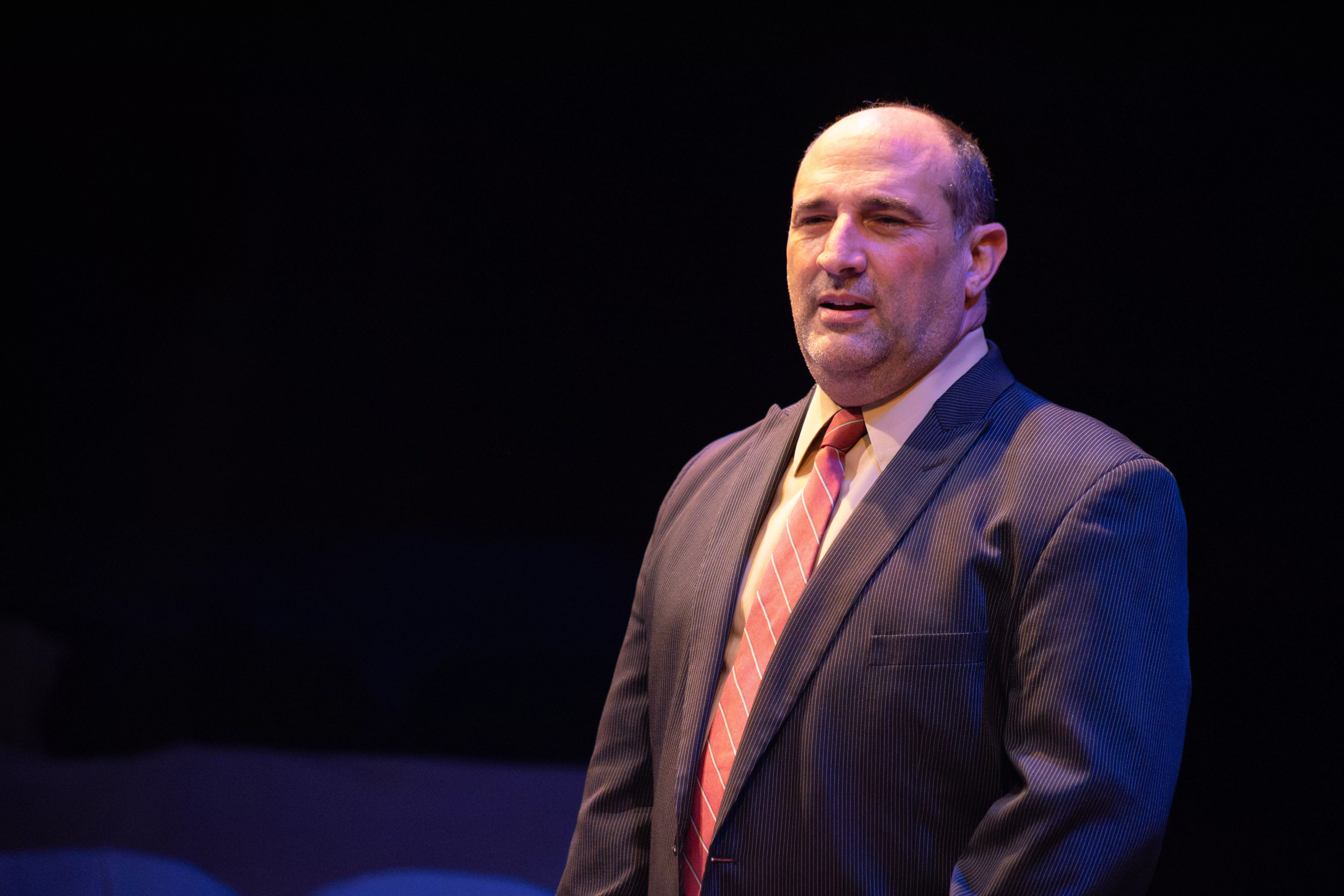 Man in suit stands to introduce himself